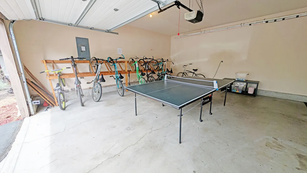 An interior space houses a ping pong table and multiple bicycles lined up against the wall, ready for adventure. The room feels casual and functional, suggesting easy access to recreational amenities for guests of all ages.