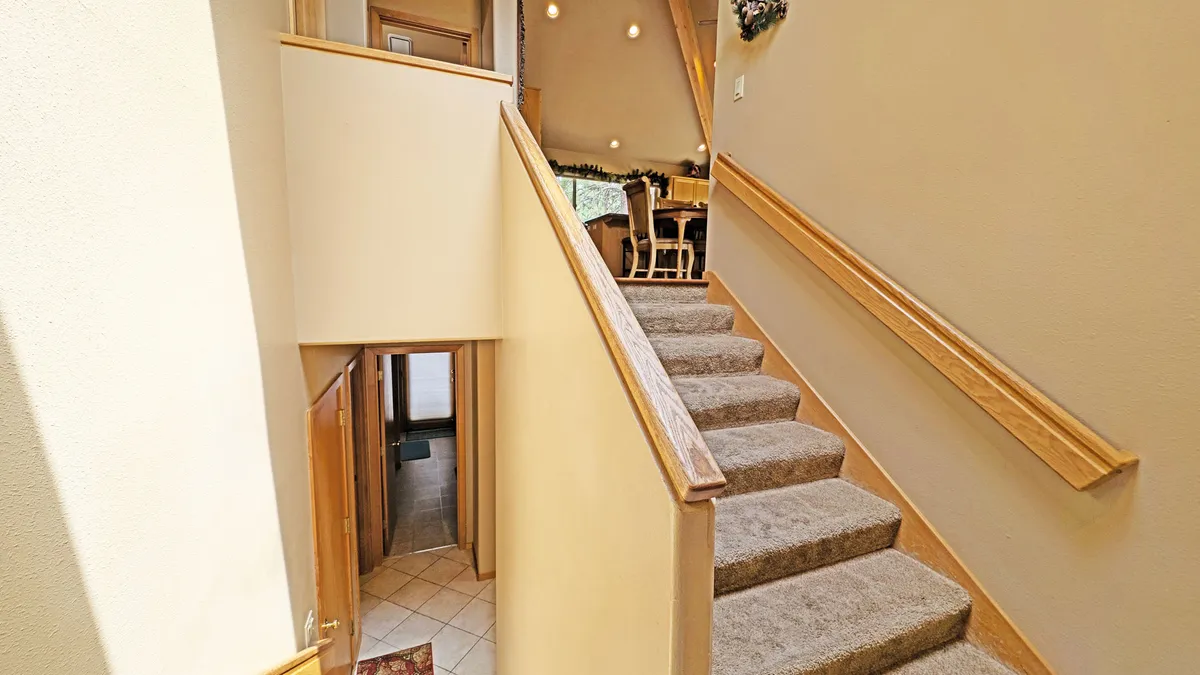 This image features a staircase and a doorway leading to a dining area in the background. The scene captures an inviting, transitional space that hints at the movement between indoor comfort and the potential for outdoor adventure, suggesting group gatherings, family meals, or returning home after exploring Sunriver's seasonal activities.