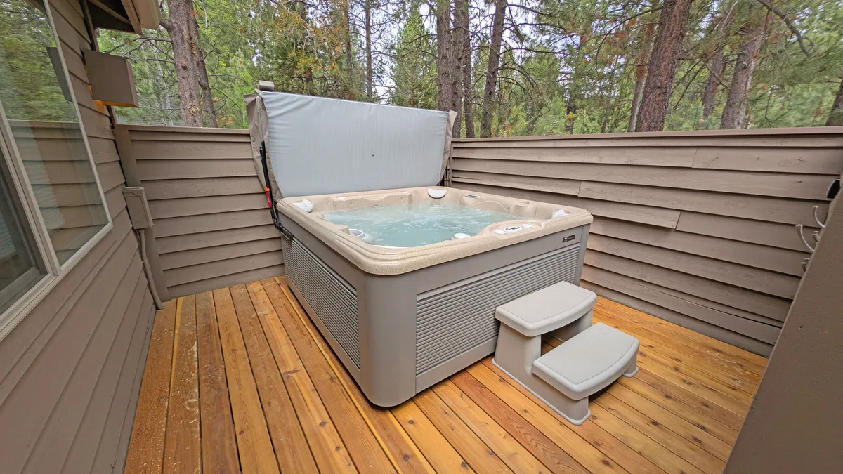 This image captures an inviting hot tub set on a wooden deck, surrounded by tall trees, creating a tranquil natural retreat. The scene evokes relaxation and outdoor enjoyment, with the hot tub serving as a focal point—perfect for unwinding after a day of activities.