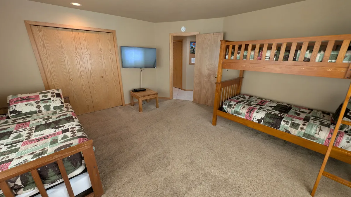 A cheerful, kid-friendly bedroom featuring a bunk bed, single bed, TV, and wooden furniture. The setup encourages play, movie nights, and group fun—ideal for families with children seeking both rest and entertainment after enjoying the resort amenities.