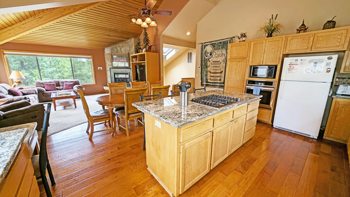 This image captures the heart of the home: an open-concept kitchen island, a spacious dining table, and a comfortable living area. The setup makes clear reference to shared meals, group gatherings, and a layout that encourages community and togetherness.