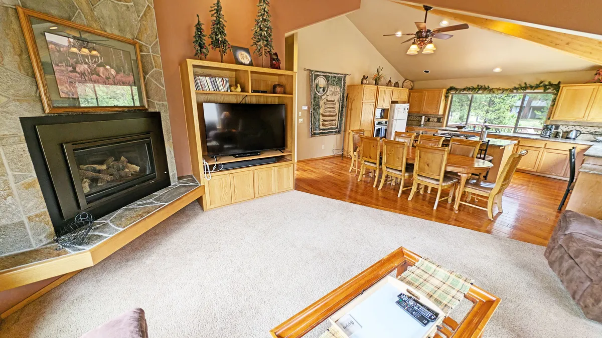 A cozy, inviting angle showcasing the gas fireplace as a focal point. The image also features the dining table, kitchen area, and a TV unit, suggesting opportunities for both relaxation and entertainment. The combination of these elements creates a homely, multifunctional environment.